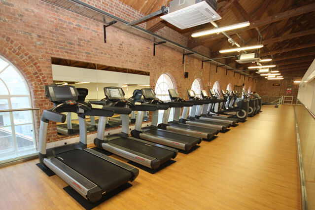 A public gym and several treadmills under ceiling-mounted air conditioning units